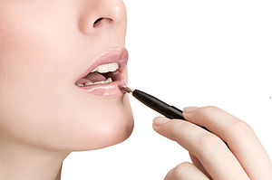 Woman applying cosmetics to her lips.